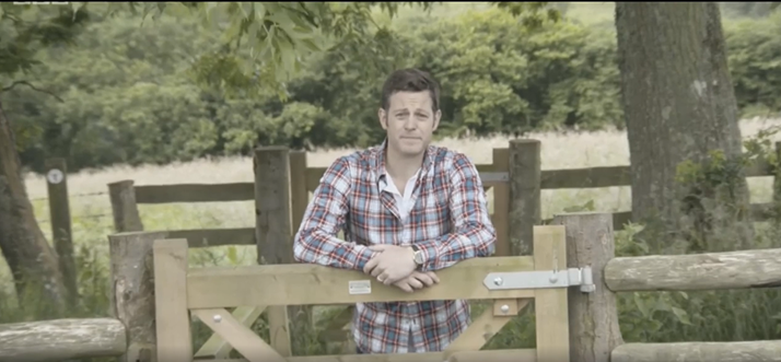 Still from video mentioned in caption below, showing Television Presenter Matt Baker leaning on a wooden gate in the countryside