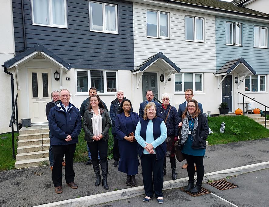 group of 11 people standing outside a row of modern terraced houses