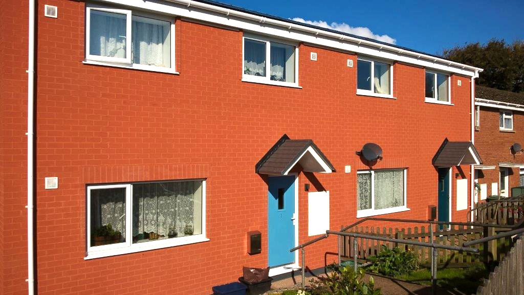 Exterior of some red brick terraced houses with blue front doors