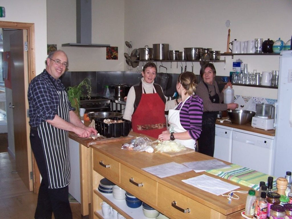 interior of kitchen showing a man on the left and three women on the right preparing food