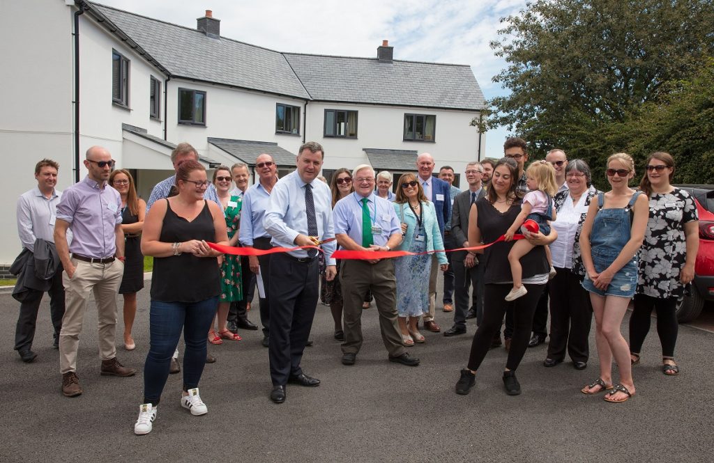 large group of people with a man cutting a ribbon